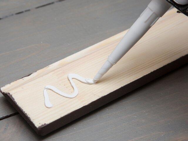 Applying grab adhesive in a zigzag pattern to a wooden board for strong bonding