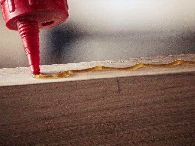 Applying wood adhesive along the edge of a timber board for strong woodworking joints