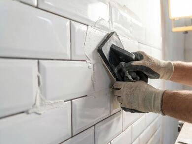Applying grout between wall tiles using a grout float for a smooth finished surface