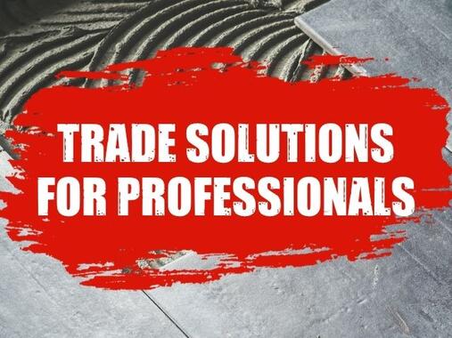 Trade Solutions for Professionals banner displayed on a floor tiling installation scene, showing tile adhesive applied with a notched trowel and large format tiles being positioned.