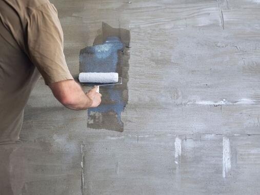 Applying diluted PVA to a wall with a roller to seal and prepare the surface before decorating