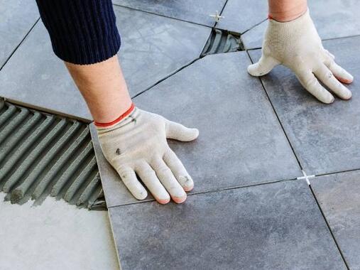 Installing floor tiles onto adhesive bed for a durable and level tiled surface