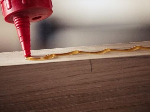 Applying wood adhesive along the edge of a timber board for strong woodworking joints