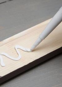 Applying grab adhesive in a zigzag pattern to a wooden board for strong bonding