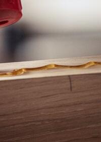 Applying wood adhesive along the edge of a timber board for strong woodworking joints